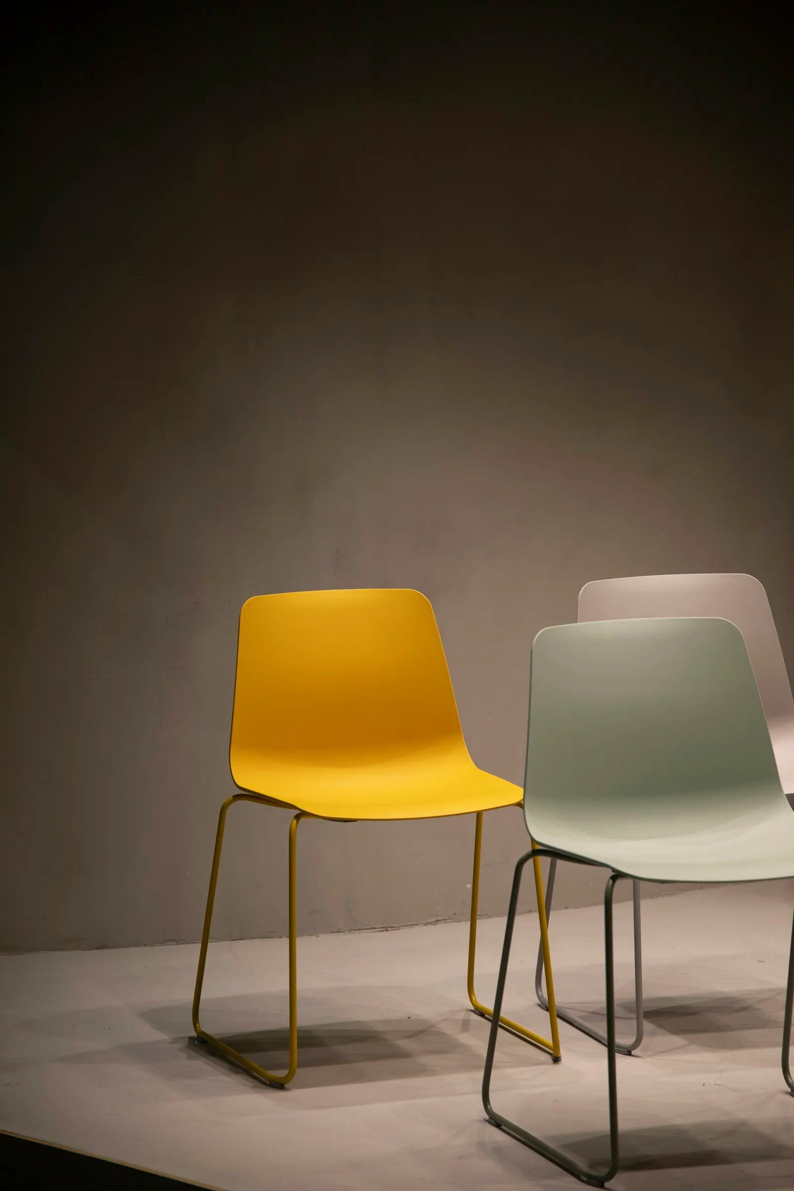Cadeiras em contexto de showroom com fundo escuro — ambiente de exposição comercial de produto.